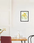 Minimal dining area with small table, chairs, glassware, and De Long Grauves Premier Cru Côte des Blancs Framed on white wall.