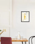 A minimalist dining area with a wooden table, glassware, and a De Long Oiry Grand Cru, Côte des Blancs Framed map on a white wall.