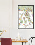 The De Long Wine Map of Italy Framed hangs above a dining table set with glassware, chairs, and a plant.
