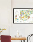 A De Long Wine Map of Spain & Portugal Framed hangs above a dining table with chairs and a glass carafe.