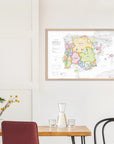 A De Long Wine Map of Spain & Portugal IGPs, framed, hangs above a table with carafe, glass, vase, and chair.