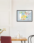 A De Long Wine Regions of Spain Vino One Framed map hangs above a dining table with chairs and a small plant.