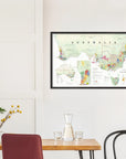 The De Long Wine Map of Australia Framed hangs on a white wall above a dining table with chairs and a glass carafe.