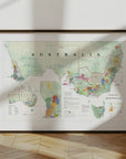 The De Long Wine Map of Australia Framed leans against a white wall, sunlight casting shadows on the wooden floor.