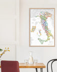 A De Long Wine Map of Italy IGTs Framed hangs on a white wall above a small dining table with minimalist decor.