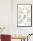 A De Long Wine Map of New Zealand Framed hangs above a table set with glassware and yellow flowers.