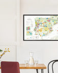 A De Long Wine Map of Spain & Portugal Framed hangs above a dining table with chairs and a glass carafe.