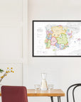 A De Long Wine Map of Spain & Portugal IGPs Framed hangs above a wooden table with a carafe, glasses, and a plant.