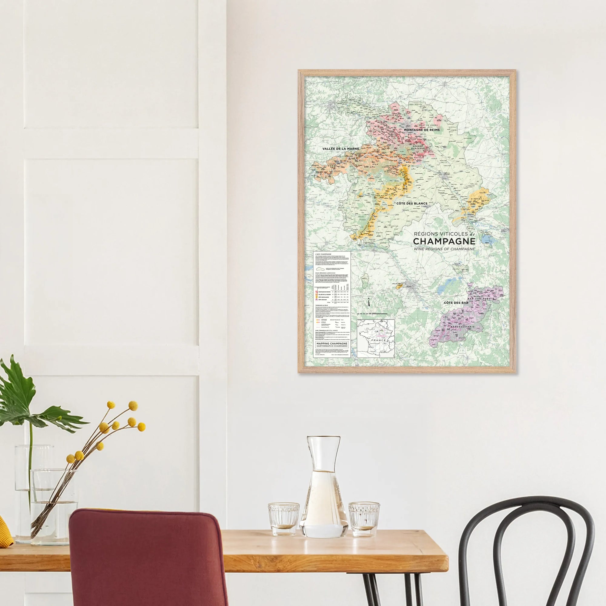 De Long's Wine Regions of Champagne Framed map in A1 size displayed above a dining table with chairs, vase, and carafe.