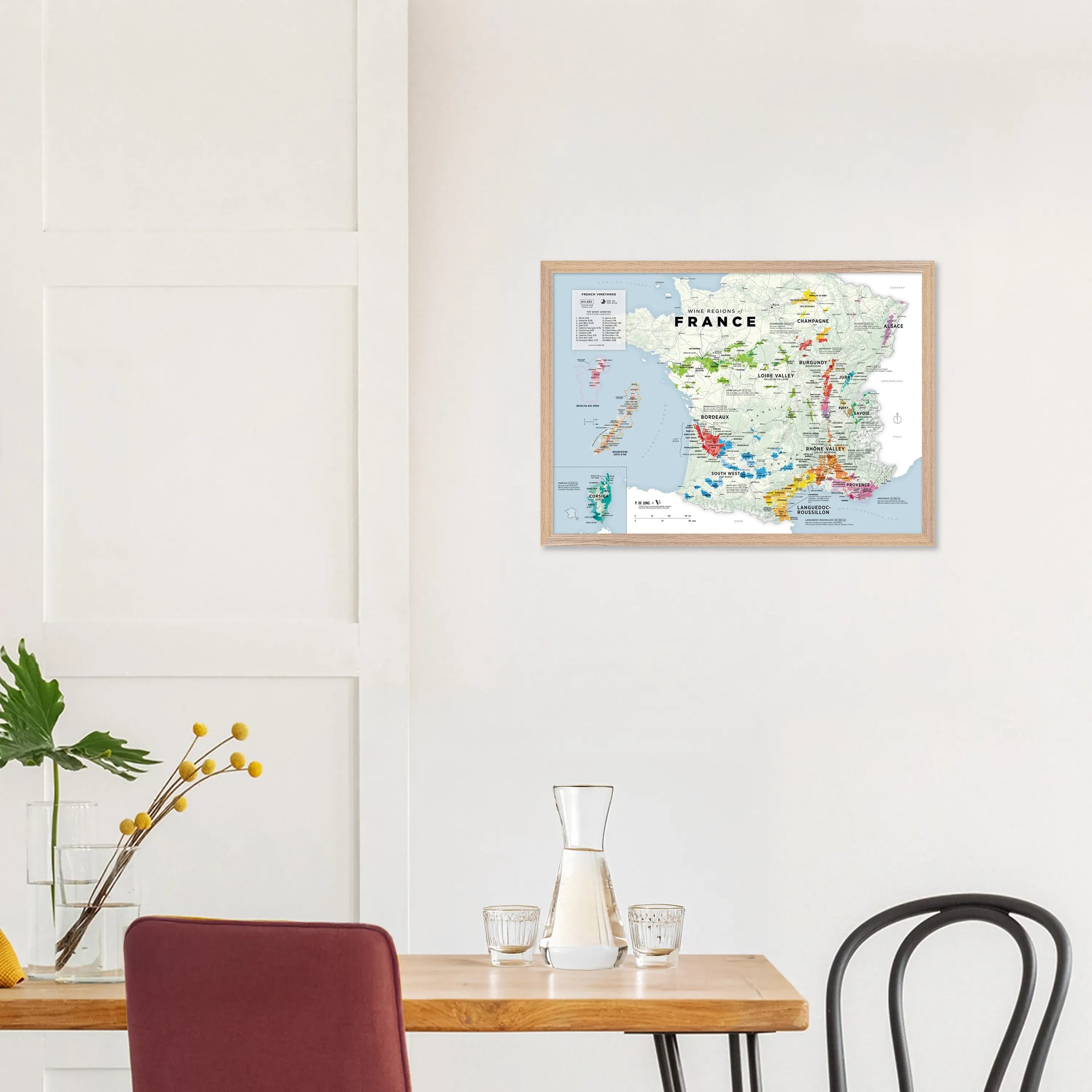 A dining area with a wooden table, chairs, and a De Long Wine Regions of France Vino One Framed map on the wall.