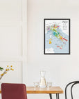 The De Long Wine Regions of Italy Vino One Framed map hangs on a white wall above a table with chairs and decor.
